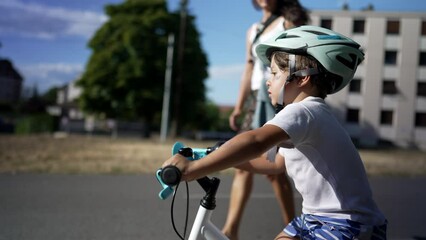 Wall Mural - Child riding bike outdoors wearing protective helmet. Active little boy exercising learns to ride bike in balance