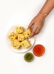 Vertical top view of Dhokla Gujarati on a white plate with two sauces on the side