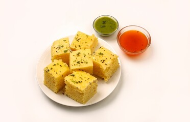 Closeup of Dhokla Gujarati on a white plate with two sauces on the side