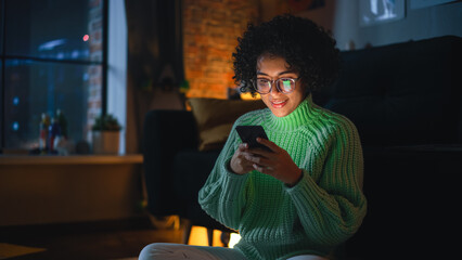Aufkleber - Latin Concentrated Woman Typing Message on her Smartphone in the Evening at Home. Internet Addicted Female Using Mobile Phone App for Online Shopping, Social Media, Browsing.