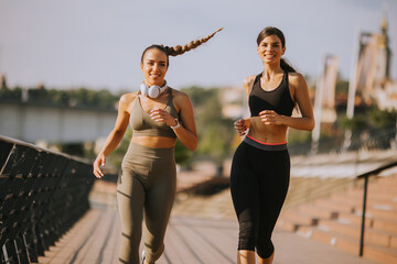 Wall Mural - Young woman taking running exercise by the river promenade