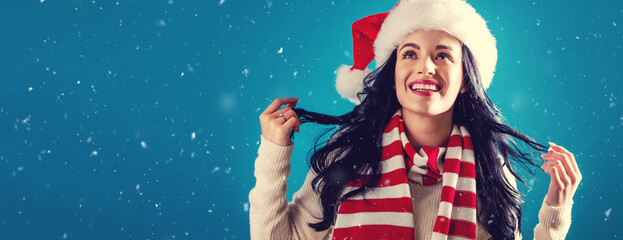 Wall Mural - Happy young woman with a Santa hat in a snowy night