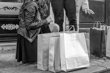 Two beautiful girls shopping along the city streets, detail on legs and shopping bags