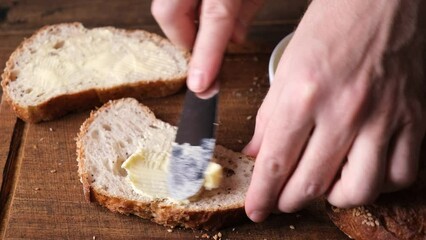 Wall Mural - Spreading butter on wheat bread on a wooden table background. Bread and butter toast