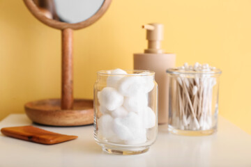 Wall Mural - Container with soft cotton wool on table near yellow wall