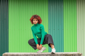 Wall Mural - young woman in the street dancing outdoors on green background