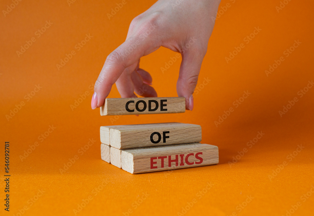 Code of ethics symbol. Concept words Code of ethics on wooden blocks. Beautiful orange background. Businessman hand. Business and Code of ethics concept. Copy space.