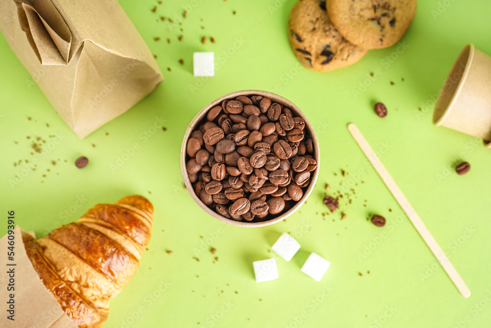 Paper cup of coffee beans on green background