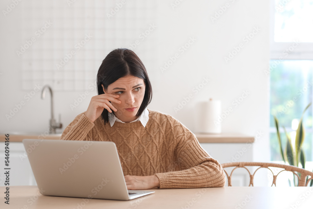 Upset young woman video chatting with psychologist in kitchen