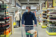 © Alexander - A young man in a protective face mask in a supermarket. Food and drinks. Pandemic