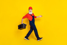 Full Length Photo Of Optimistic Senior Engineer With White Beard Red Helmet Hold Tool Box Walking Isolated On Yellow Color Background