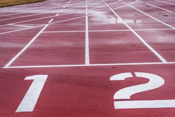 Lane number one and two at the starting line of a wet red running track.