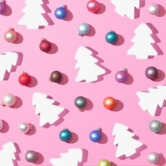 Wall Mural - Trendy Christmas pattern made with colorful baubles decoration and christmas tree on pink background with the sharp shadows of the winter sun. Minimal Concept New Year's and Christmas atmosphere.