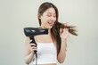 © KMPZZZ - Hair Dryer, beautiful happy, asian young woman, girl hand in using, holding hairdryer to dry, blowing blonde long straight after shower at home. Hairdressing, hair treatment isolated on background.