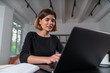 © VideoFlow - Smiling attractive businesswoman typing on laptop at office workplace