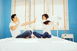 Playful asian couples use pillow fights on their mattresses because they resent something that men do not indulge and do as their girlfriend orders to make stupid women fight but men give up.

