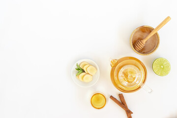 Wall Mural - Top view of a cup of tea with ginger root, lime, cinnamon and teapot on white background. Health drink concept.