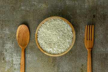 uncooked rice or dry rice. raw rice in wooden bowl with wooden spoon and fork