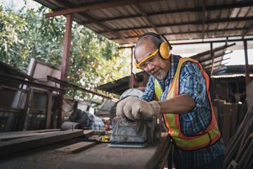 Wall Mural - An elderly carpenter works the wood with meticulous care.