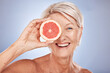 Beauty, mature woman and grapefruit portrait with a woman for skincare and wellness on a grey studio background. Cosmetic, fruit and citrus with fresh food for healthy skin care and anti aging