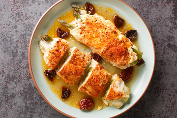 Grilled chicken breast stuffed with mozzarella, asparagus and tomatoes close-up in a plate on the table. Horizontal top view from above