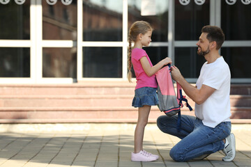 Canvas Print - Happy father preparing his daughter to school outdoors. Space for text