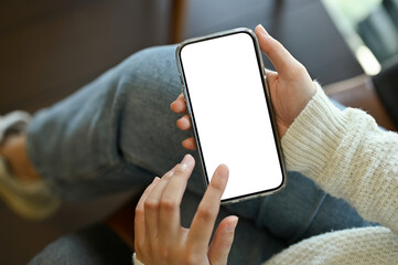 A female using her smartphone while sitting in the coffee shop. smartphone white screen mockup.