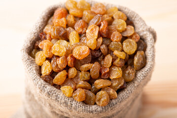 Poster - Linen bag of raisins on wooden table. Beautiufl studio photo of raisins