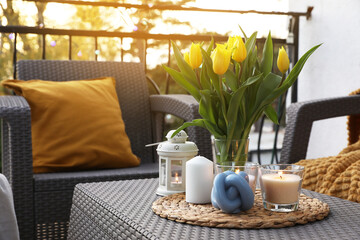 Sticker - Soft pillow, blanket, burning candles and yellow tulips on rattan garden furniture outdoors