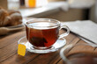 Tea bag in glass cup on wooden table indoors, closeup