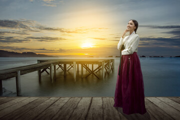 Canvas Print - Asian woman wearing a traditional Korean national costume, Hanbok, standing on wooden pier