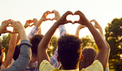 Wall Mural - Happy adult diverse multiethnic people raise hands up in air, do heart shaped gestures, share good vibes, hope for peaceful future, send kind wishes to universe. Outdoor outside back view group shot