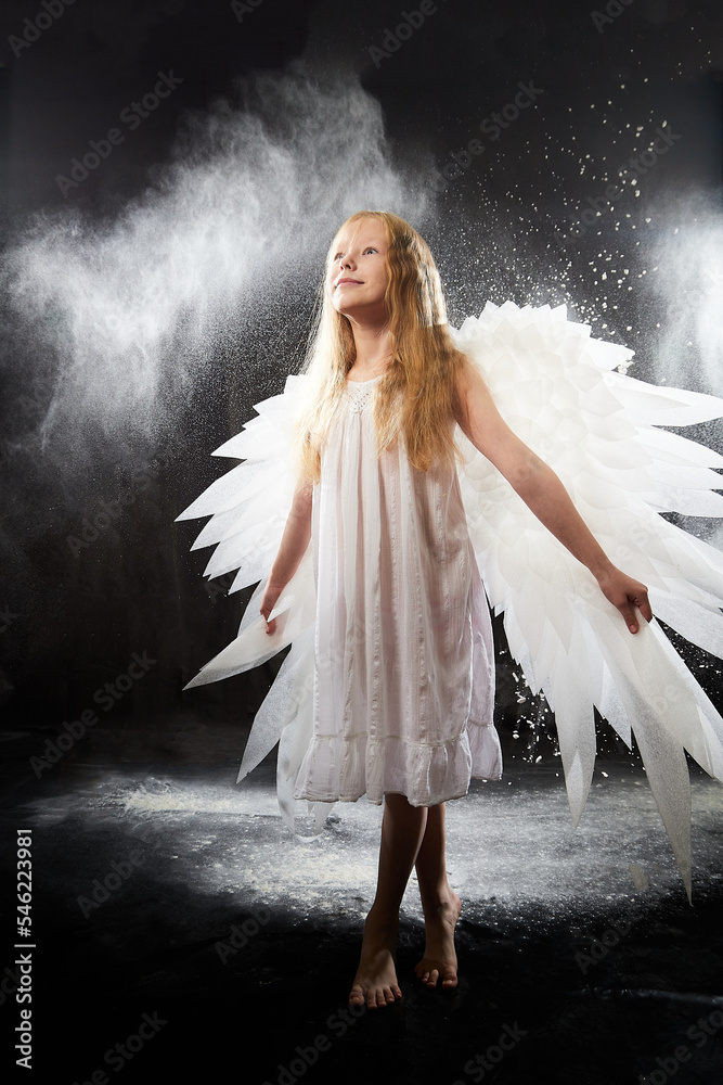 A girl in a white shirt, wings and with long hair, looking like a angel ...