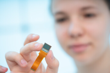 Poster - girl holds in her hands the sensor of a miniature video camera for hidden shooting