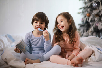 Wall Mural - A family with children having fun on the bed under the covers during the Christmas holidays.