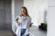 © dianagrytsku - Young woman using smartphone leaning at kitchen table with coffee mug and organizer in a modern home.