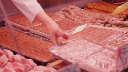 Wall Mural - Womans hands arranging minced meat in plastic containers in a window shop. Female placing meat in a refrigerator.