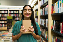 Cheerful young woman buying an interesting book at the shop