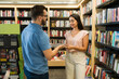 © AntonioDiaz - Caucasian man at the bookstore flirting with a smiling woman