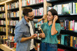 © AntonioDiaz - Attractive flirty man talking with a happy woman while at the bookstore