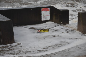 Waves crashing over the sea wall onto a no access sign. Taken in Blackpool Lancashire England. 