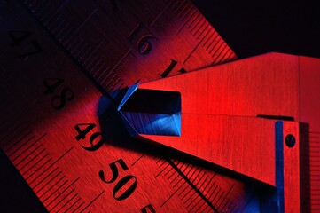 Wall Mural - caliper and metal rulers illuminated in red and blue. close-up