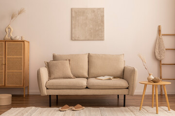 Creative composition of living room interior with mock up poster frame, beige sofa, round wooden coffee table, vase with dried flowers, bright rug, rattan commode and personal accessories. Home decor.