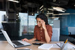 © Liubomir - Businesswoman disappointed and sad at work, not happy with the result of achievement at work, Hispanic woman desperate and sad working inside office using laptop at work.