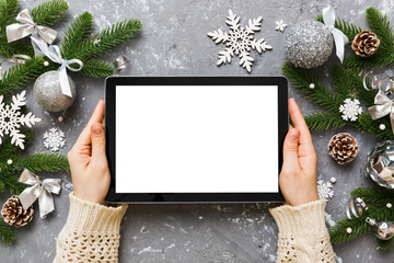 Wall Mural - Christmas online shopping from home, female hands holding tablet pc with blank white display top view. woman hand holding tablet with blank screen, Christmas tree and gifts on background