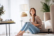 © sepy - Smiling caucasian woman using laptop at home while sitting on the floor