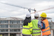 © reewungjunerr - Young and senior Engineers discuss about work of large building underconstruction,Three people working on site of under construction