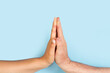 © Mercedes Fittipaldi - Mano de mujer y hombre tocandose sobre un fondo celeste pastel liso y aislado. Vista de frente y de cerca. Copy space