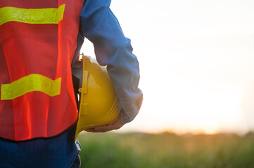 Wall Mural - Close up hand holding white helmet hard hat Engineering concept, Technician holding hard hat safety hard hat sunlight background