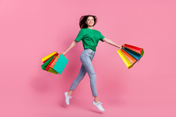 Wall Mural - full size profile portrait of excited lovely girl arms hold packages jump isolated on pink color bac